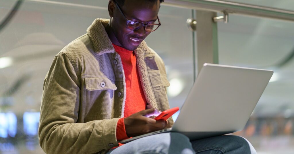 image of a man using a laptop and smart phone